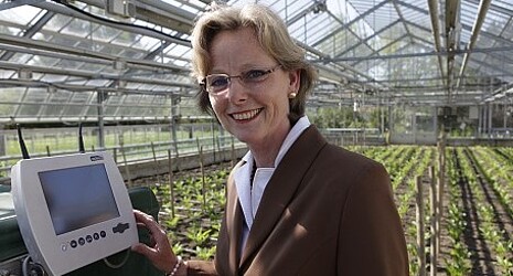 Mrs. Dr. Wolf stands in the greenhouse and analyzes the development of the plants